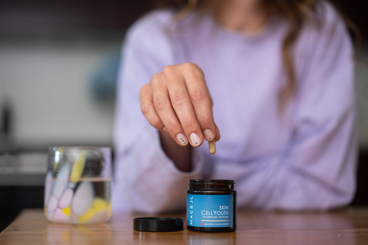 Eine Hand nimmt eine Kapsel aus der Dose MACELL Skin CellYouth