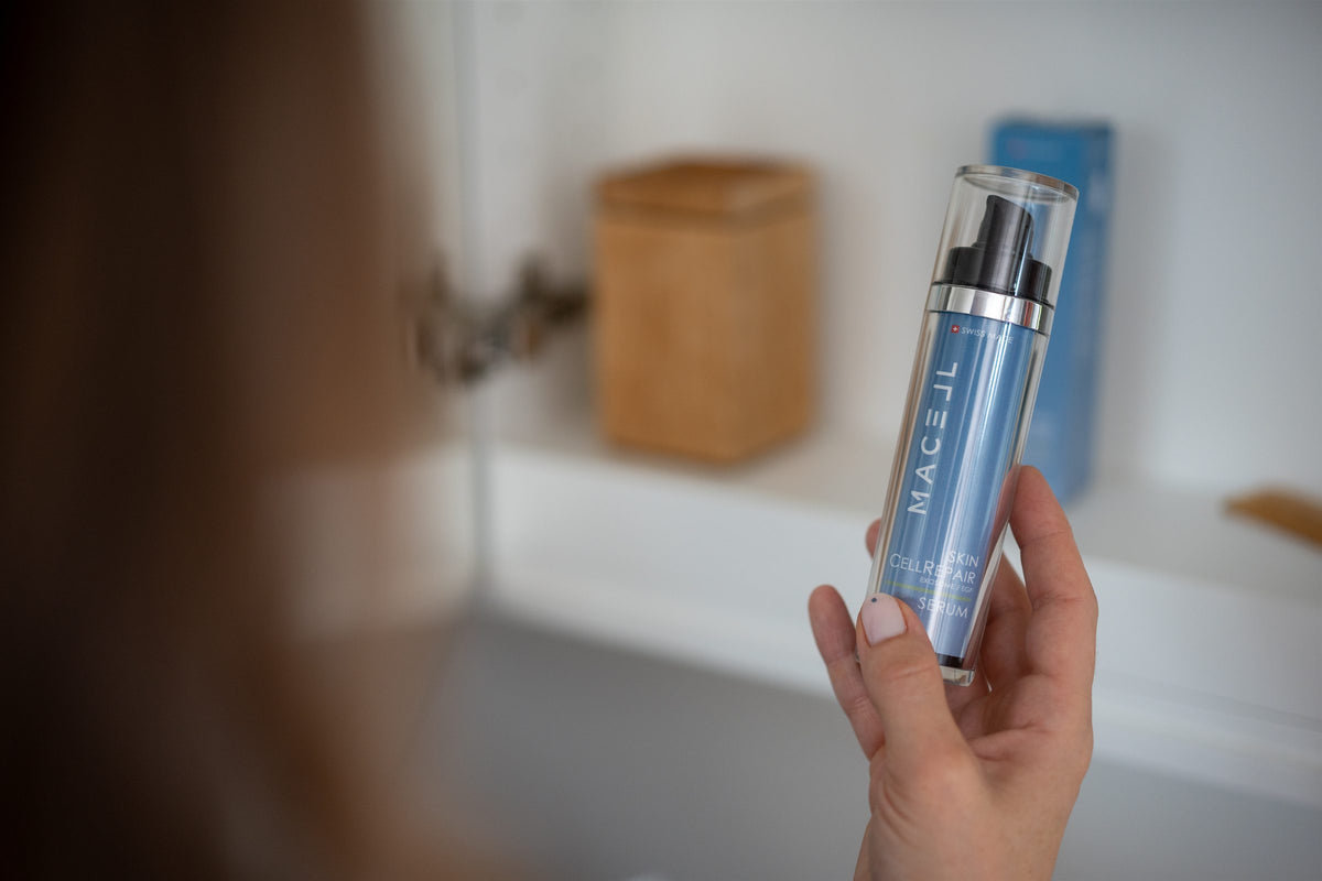 Eine Hand hält das MACELL Skin CellRepair Serum vor einem geöffneten Spiegelschrank